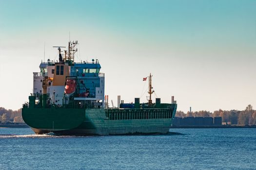 Green cargo ship entering a port of Riga, Europe