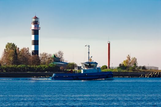 Blue small tug ship leaving Riga and entering the Baltic sea