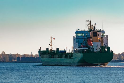 Green cargo ship entering a port of Riga, Europe