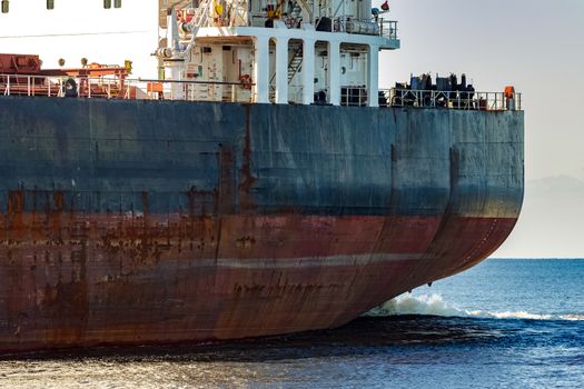 Black cargo ship's stern in still water close up. Riga, Europe