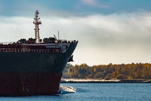 Black cargo ship's bow entering Riga, Europe