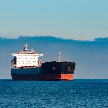 Black cargo ship moving in still Baltic sea water. Riga, Europe