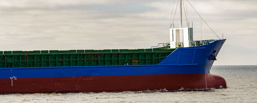 Blue cargo ship's bow leaving the port of Riga