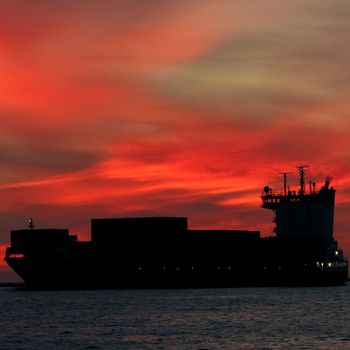 Large container ship silhouette arriving from Baltic sea at red