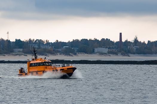 Orange pilot ship moving at speed to Baltic sea, Riga, Europe