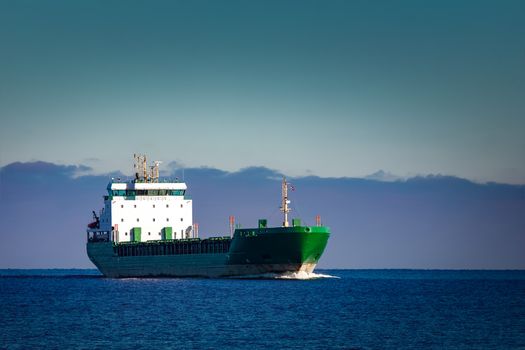 Green cargo ship moving in still water of Baltic sea