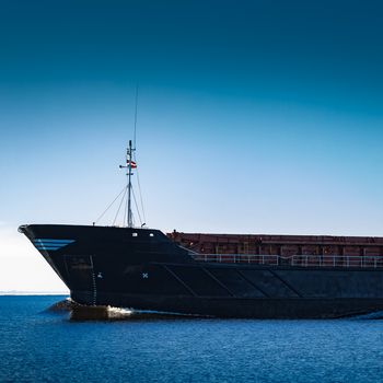 Black cargo ship's bow. Bulk carrier sailing in still Baltic sea