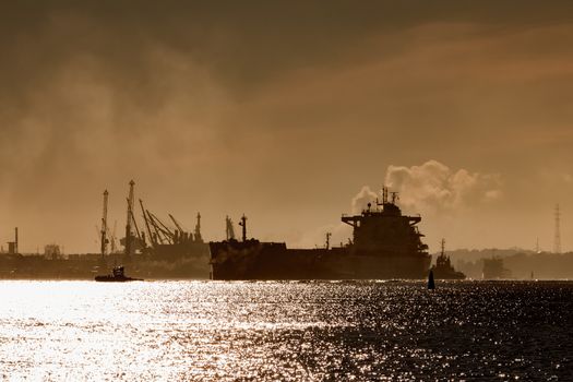 Cargo ship silhouette entering a port of Riga at the morning