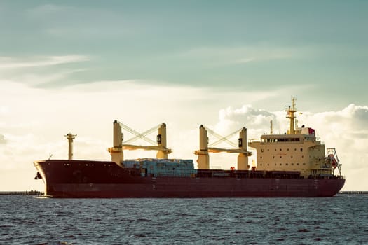 Red cargo ship moving entering the port of Riga