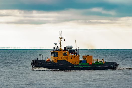 Small orange tug ship moving from the Baltic sea