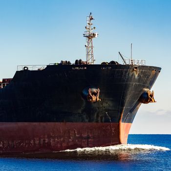 Black cargo ship's bow in still water. Riga, Europe