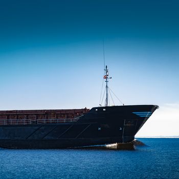 Black cargo ship's bow. Bulk carrier sailing in still Baltic sea