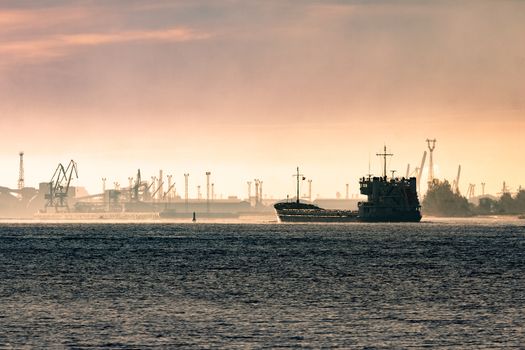 Cargo ship silhouette entering a port of Riga at the morning