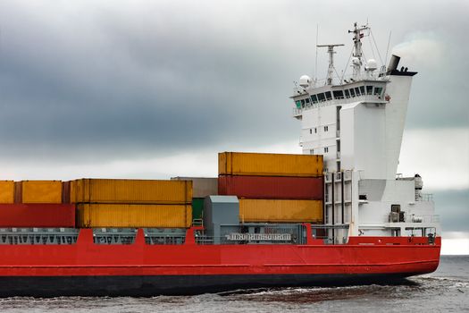 Red cargo container ship's cabin in cloudy day