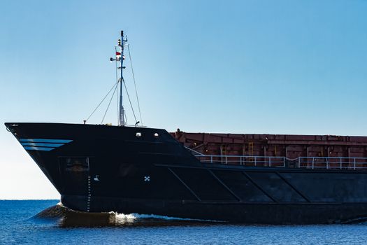 Black cargo ship's bow. Bulk carrier sailing in still Baltic sea