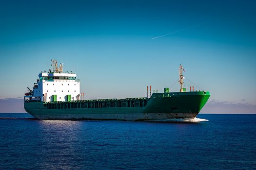 Green cargo ship moving in still water of Baltic sea