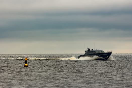 Black elite speed motor boat moving fast from Baltic sea