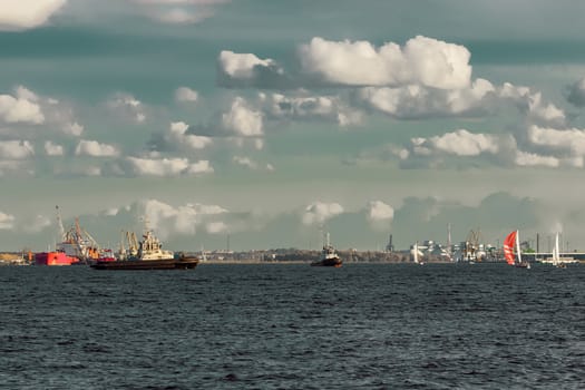 Tug ships and sailboats against cargo terminal in Riga