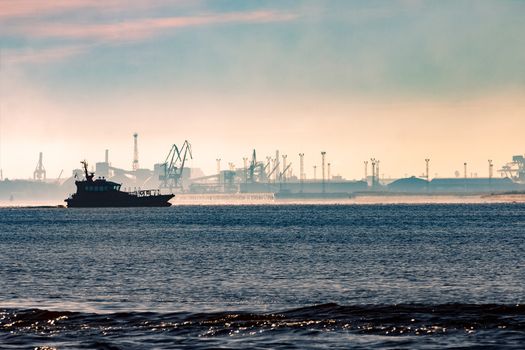 Pilot ship silhouette in the morning against the cargo port