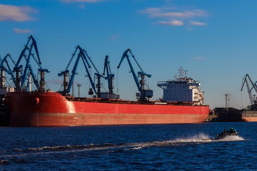 Red cargo ship loading in the port of Riga, Europe