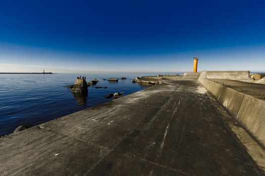 Yellow lighthouse on breakwater dam in Riga, Europe