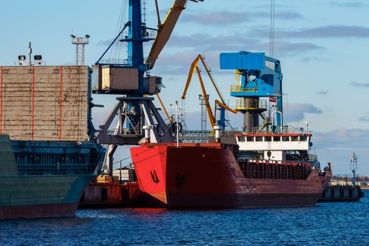 Red cargo ship loading in the port of Riga, Europe