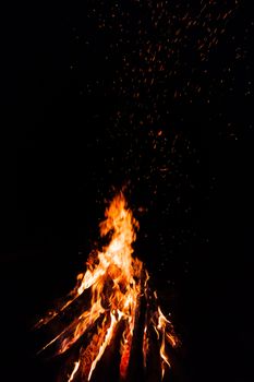 Campfire with flying sparks isolated on black background