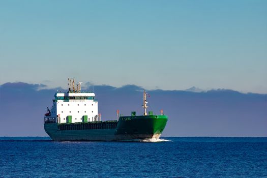 Green cargo ship moving in still water of Baltic sea