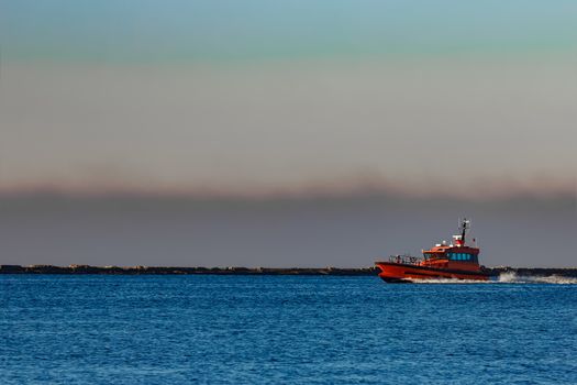 Red pilot ship moving past the breakwater dam in Riga, Europe