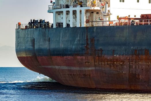 Black cargo ship's stern in still water close up. Riga, Europe