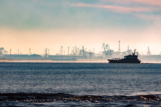 Pilot ship silhouette in the morning against the cargo port