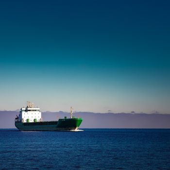 Green cargo ship moving in still water of Baltic sea