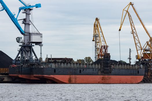 Black barge loading in cargo port of Riga