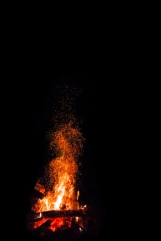 Campfire with flying sparks isolated on black background