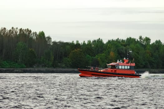 Orange pilot ship sailing on the Daugava river