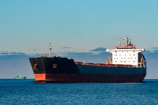 Black cargo ship moving in still Baltic sea water. Riga, Europe