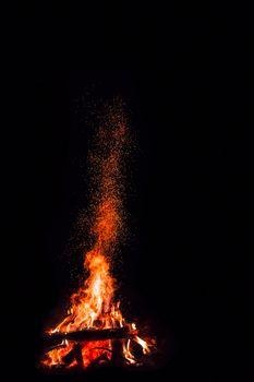 Campfire with flying sparks isolated on black background