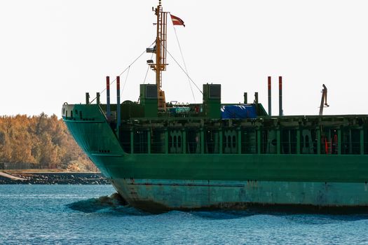 Green cargo ship's bow close up in still water, Riga