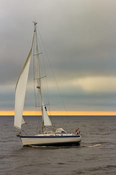 White sailboat traveling in Baltic sea in cloudy day