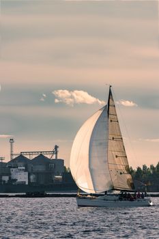 Sailboat moving on Daugava river in evening, Latvia