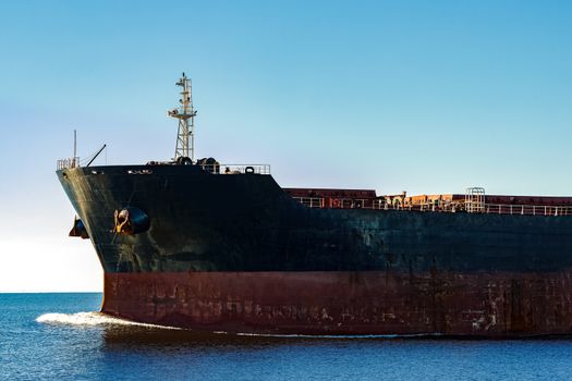 Black cargo ship's bow in still water. Riga, Europe