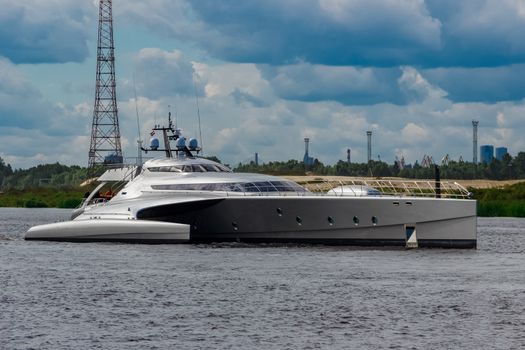 Large silver trimaran. Luxury yacht sailing by the river in Riga