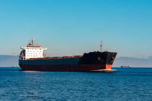 Black cargo ship moving in still Baltic sea water. Riga, Europe