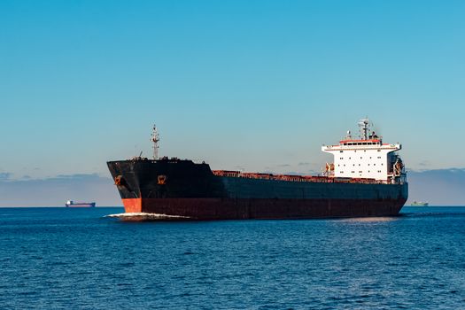 Black cargo ship moving in still Baltic sea water. Riga, Europe