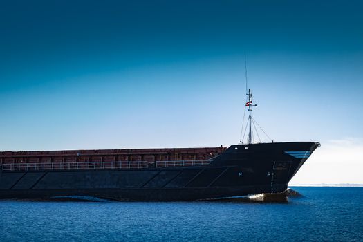 Black cargo ship's bow. Bulk carrier sailing in still Baltic sea