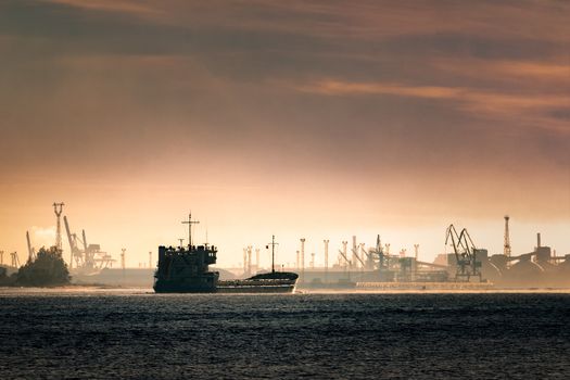 Cargo ship silhouette entering a port of Riga at the morning