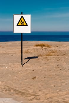 Yellow warning sign on summer beach, Riga