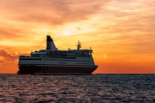 Cruise liner in open sea. Passenger ferry sailing at hot sunset