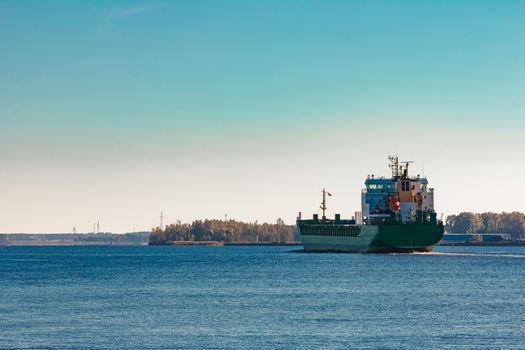 Green cargo ship entering a port of Riga, Europe