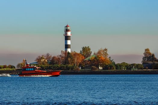 Red pilot ship moving past the lighthouse in Riga